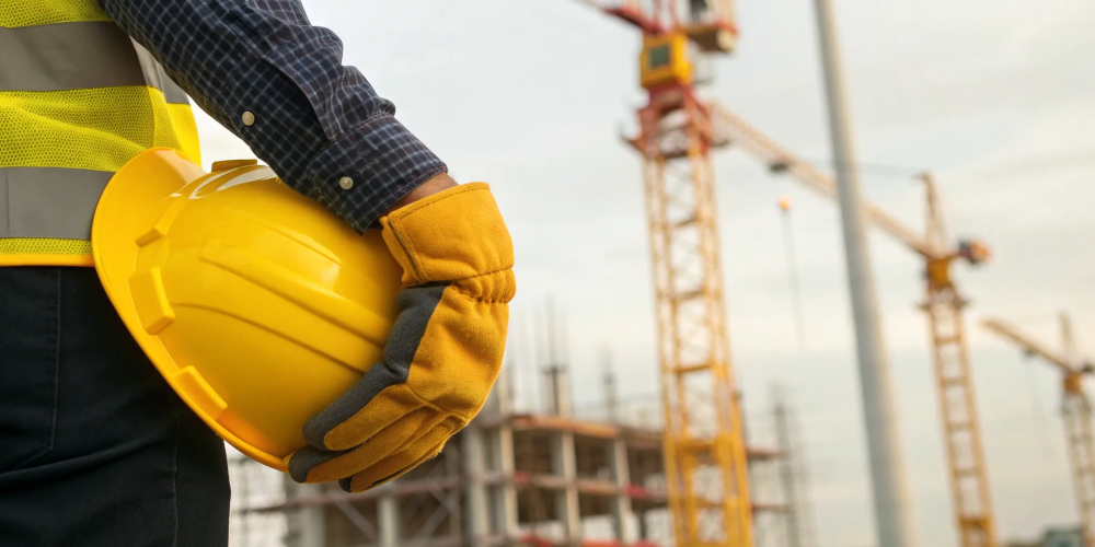Construction worker in safety gear on a job site, following essential safety rules.